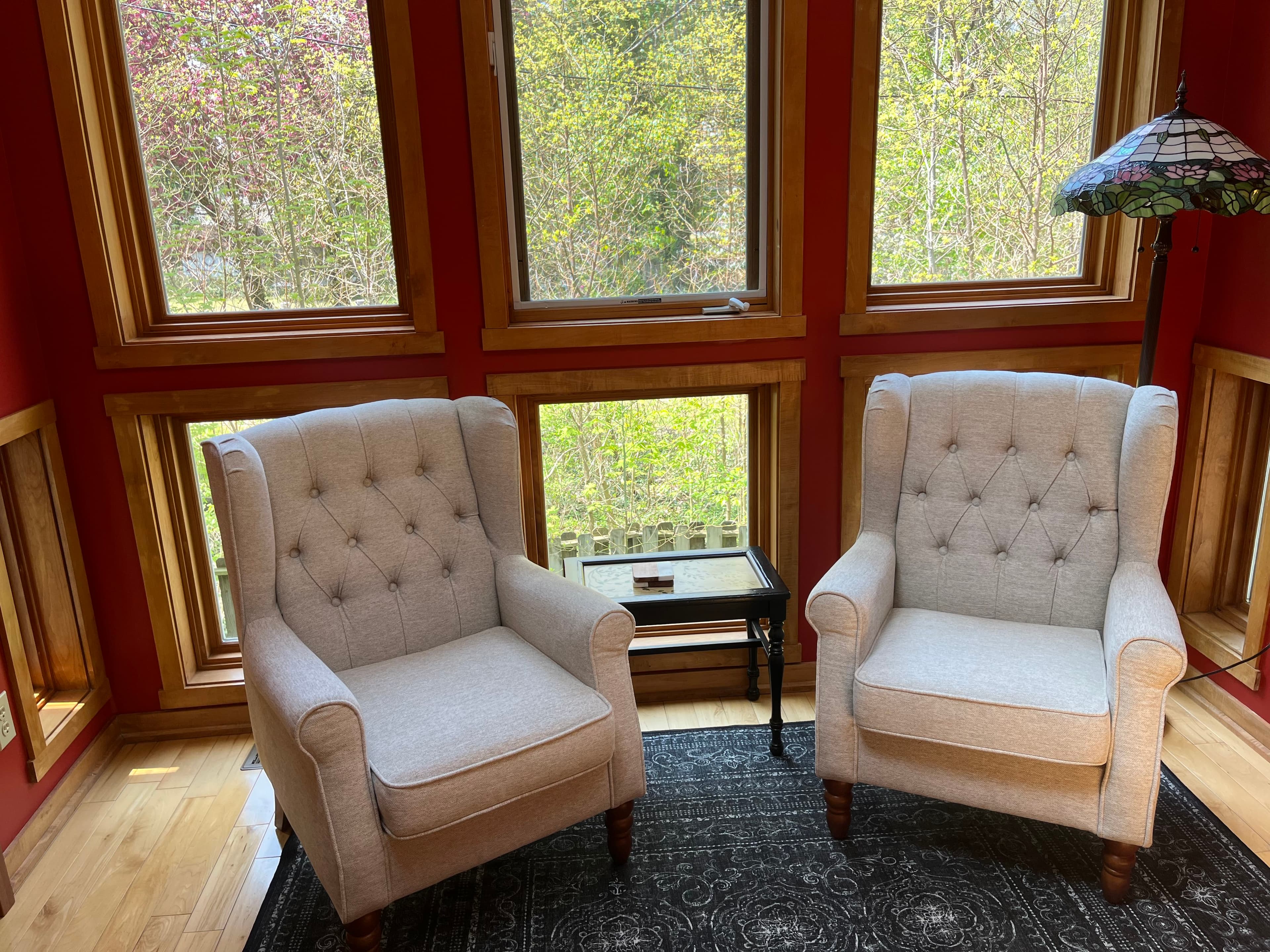 Two sitting chairs in front of large windows looking onto the trees